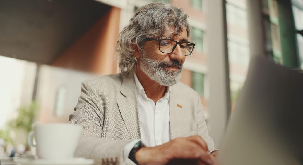 confident older man engaged with content on laptop