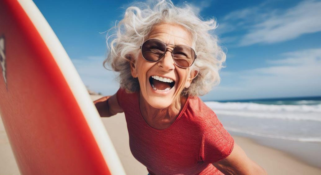 senior woman smiling with a surfboard